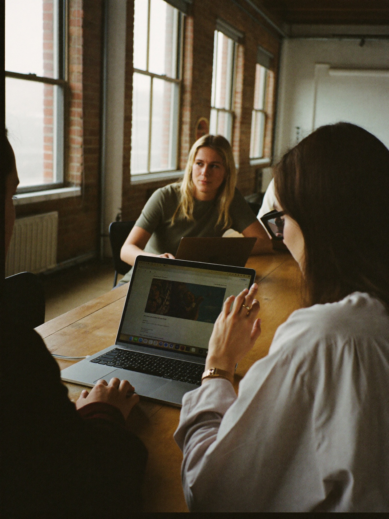 Three colleagues around a laptop in a loft office