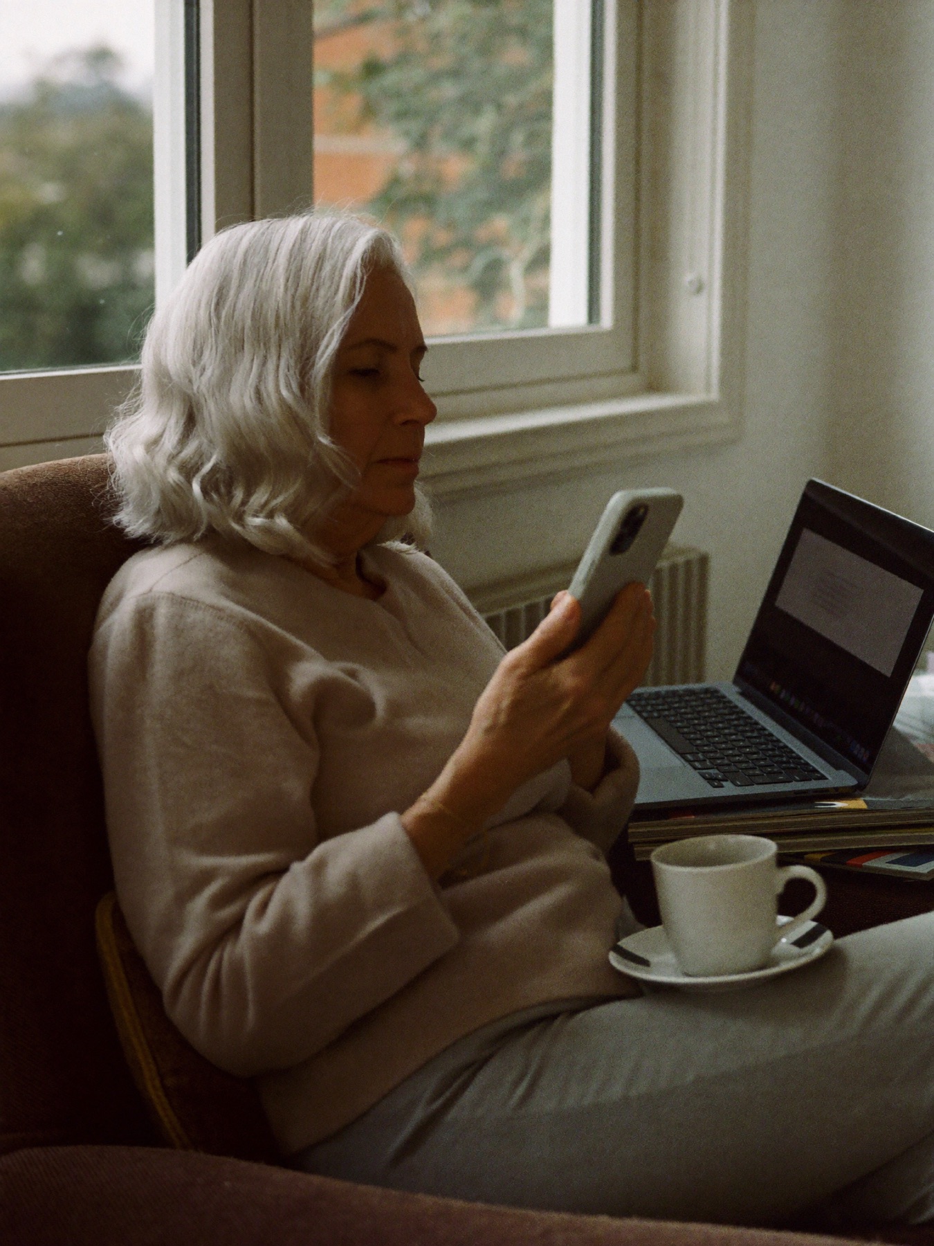 A woman reading on her phone in an armchair